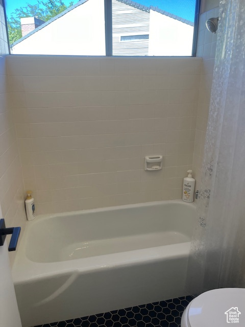 Bathroom with tile patterned floors and washtub / shower combination