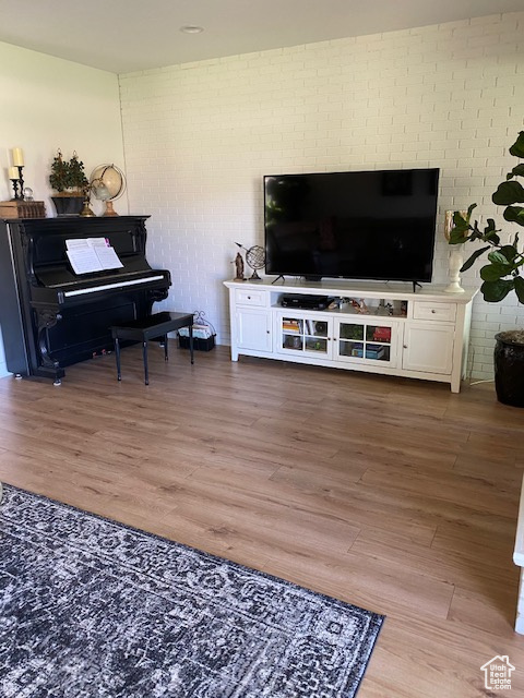 Living room featuring brick wall and wood finished floors