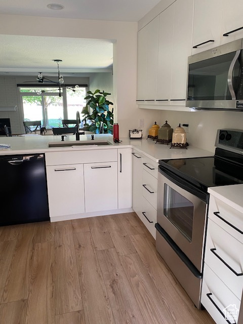 Kitchen with appliances with stainless steel finishes, light countertops, white cabinetry, and light wood-style flooring