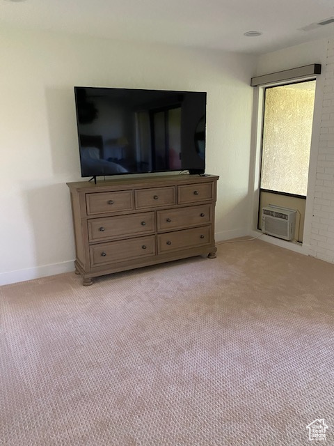 Bedroom with light colored carpet and a wall mounted AC
