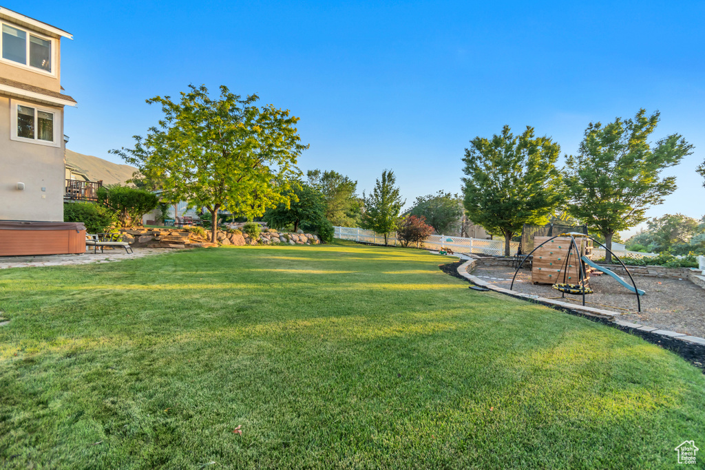 View of yard with a hot tub and a playground