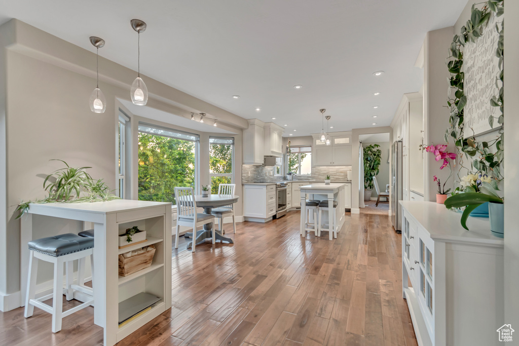 Kitchen with white cabinetry, a breakfast bar area, light wood-style flooring, tasteful backsplash, and recessed lighting