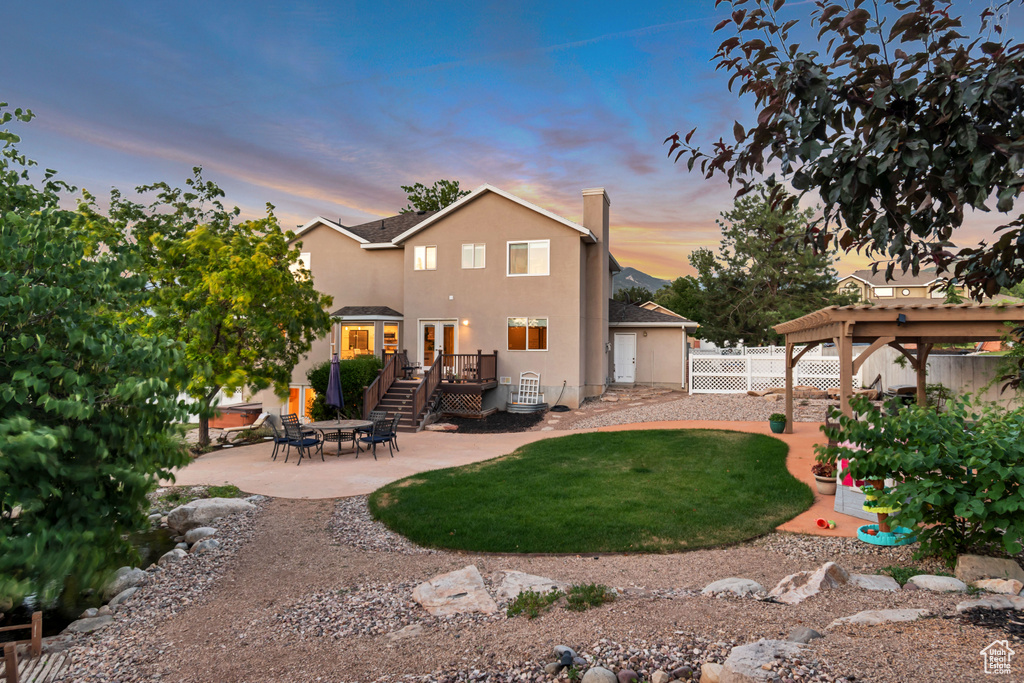 Back of property with a patio, a wooden deck, stucco siding, and a chimney