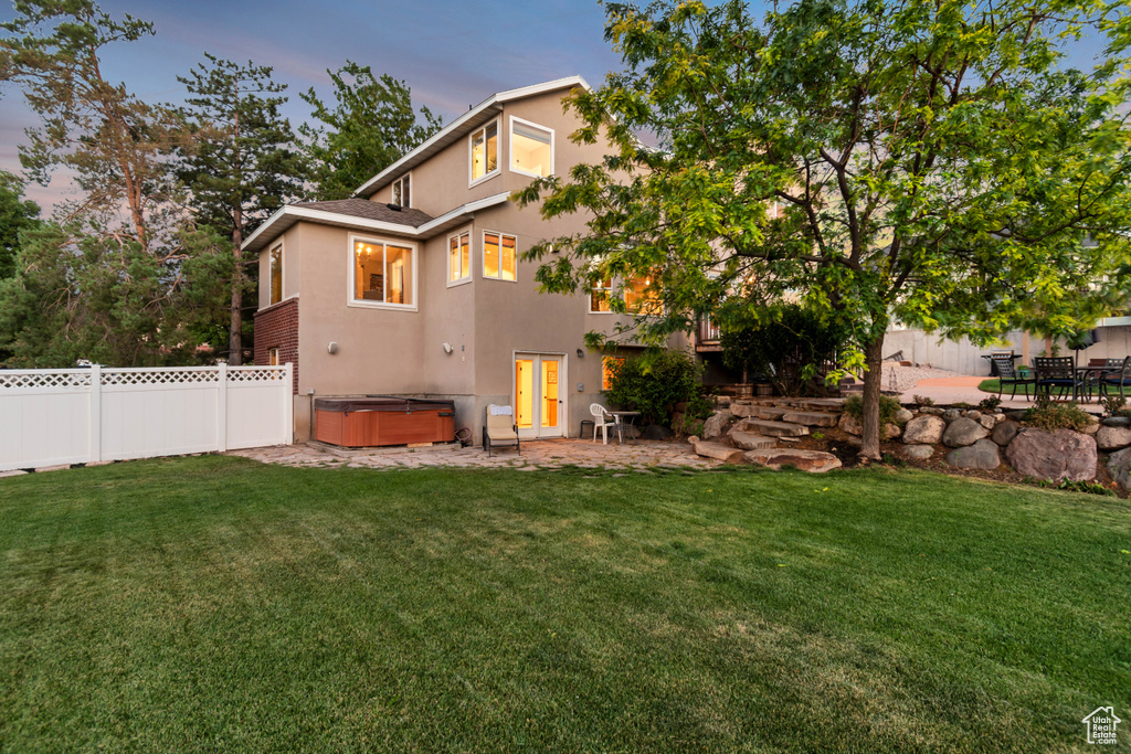 Rear view of property featuring a hot tub, stucco siding, a patio area, and a fenced backyard