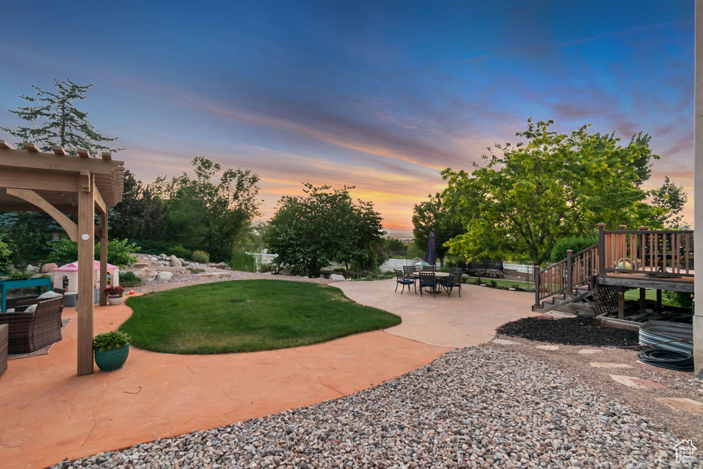 View of green lawn with a patio area and a wooden deck