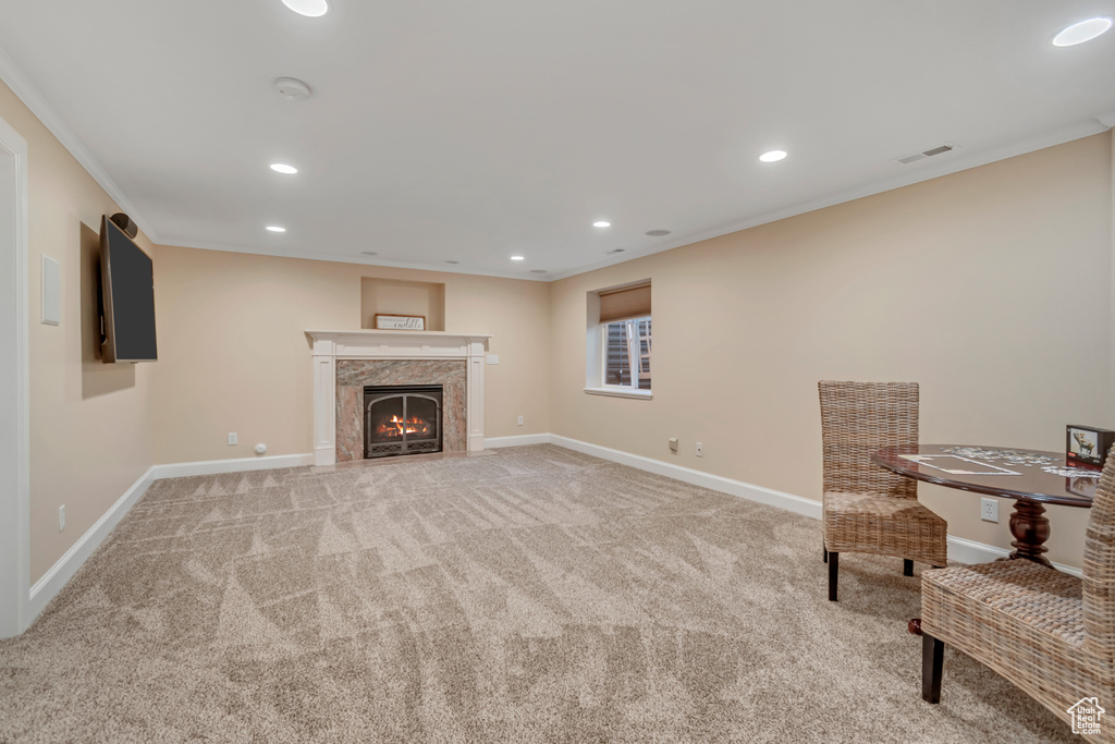 Unfurnished room featuring light colored carpet, recessed lighting, crown molding, and a warm lit fireplace