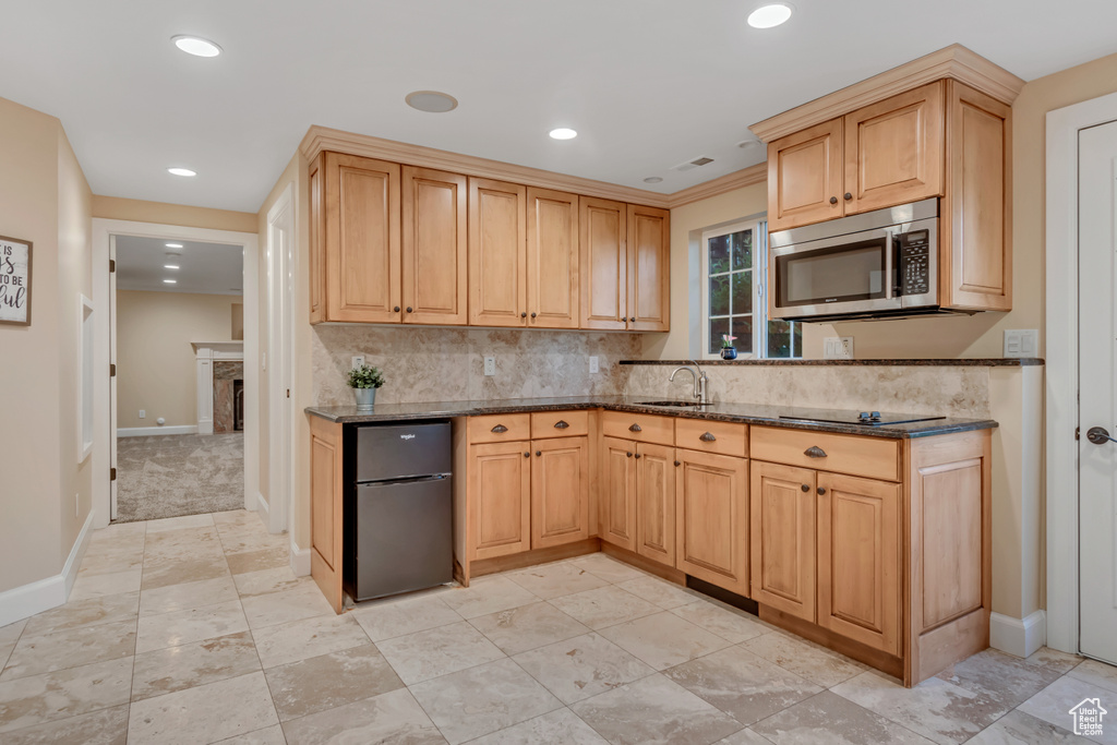 Kitchen featuring stainless steel microwave, freestanding refrigerator, dark stone countertops, tasteful backsplash, and recessed lighting