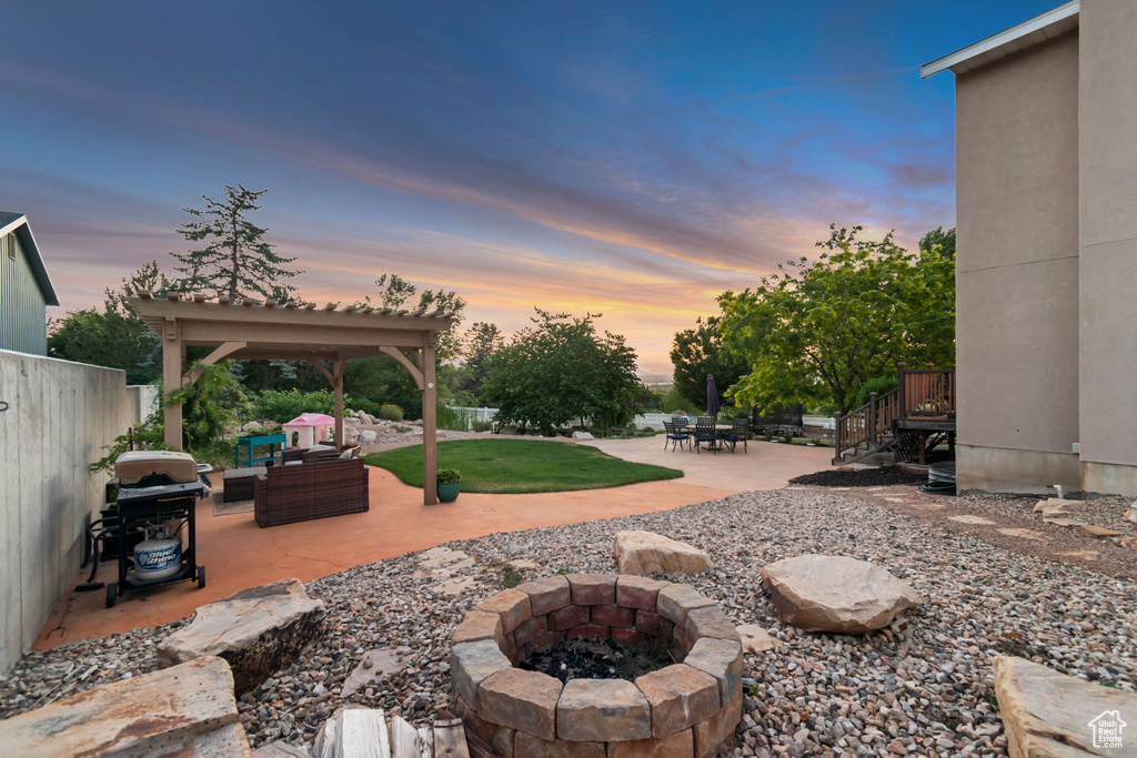 View of patio with area for grilling and an outdoor living space with a fire pit