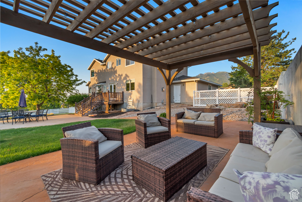 Fenced backyard with outdoor lounge area, stairs, a patio, a pergola, and a deck with mountain view