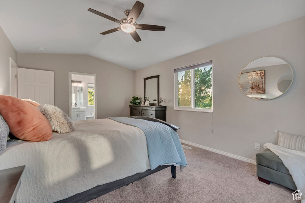 Bedroom featuring multiple windows, lofted ceiling, carpet, connected bathroom, and ceiling fan