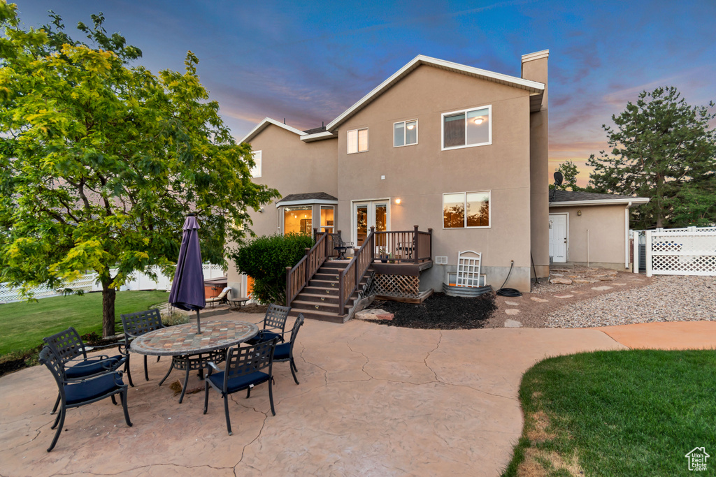 Rear view of property with stucco siding, a patio, a chimney, a deck, and french doors