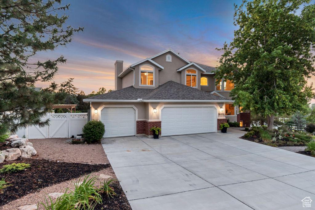 View of front of home with concrete driveway, brick siding, stucco siding, and a chimney