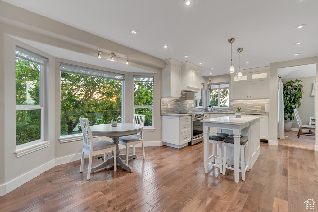 Kitchen featuring stainless steel range with electric cooktop, light countertops, tasteful backsplash, white cabinetry, and a kitchen island