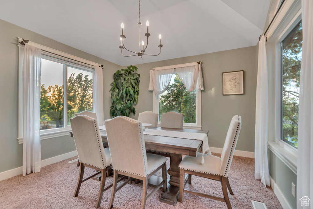 Dining area featuring lofted ceiling, a chandelier, healthy amount of natural light, and light carpet