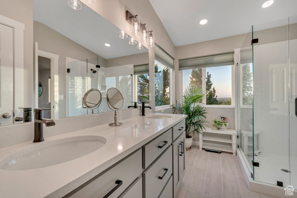 Bathroom with double vanity, a shower stall, recessed lighting, vaulted ceiling, and tile patterned flooring
