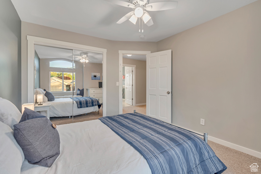 Carpeted bedroom featuring ceiling fan and a closet