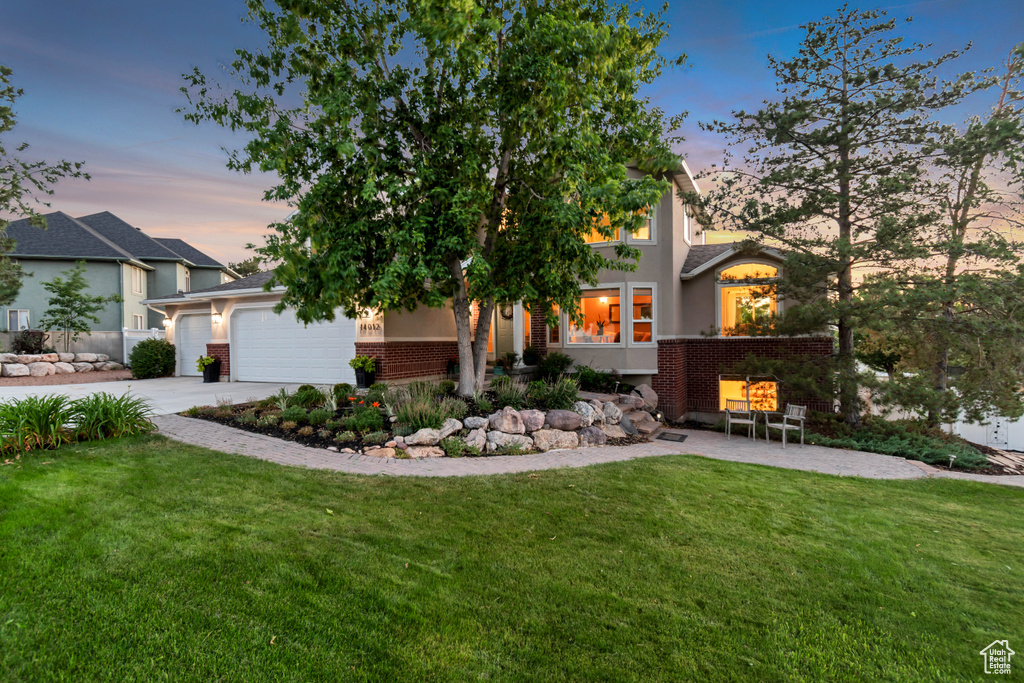 View of front facade with concrete driveway, a lawn, brick siding, and an attached garage