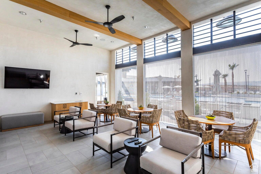 Tiled dining area with a high ceiling, beamed ceiling, and a ceiling fan