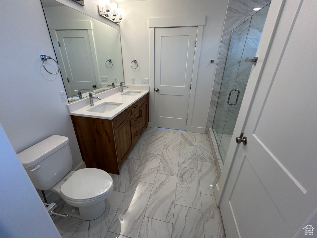 Bathroom featuring marble finish flooring, double vanity, and a shower stall