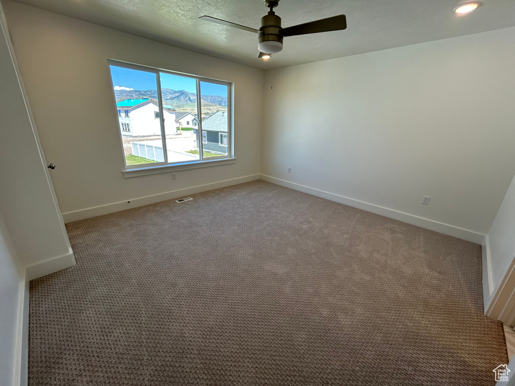 Empty room with ceiling fan and light carpet