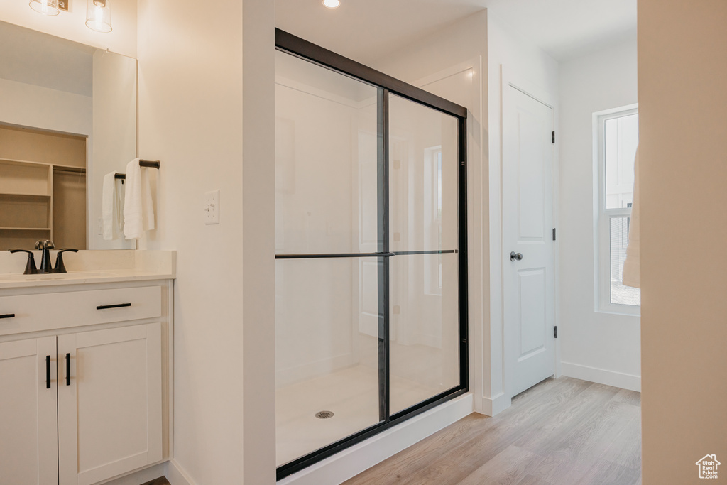 Bathroom featuring a shower stall, wood finished floors, vanity, and a walk in closet