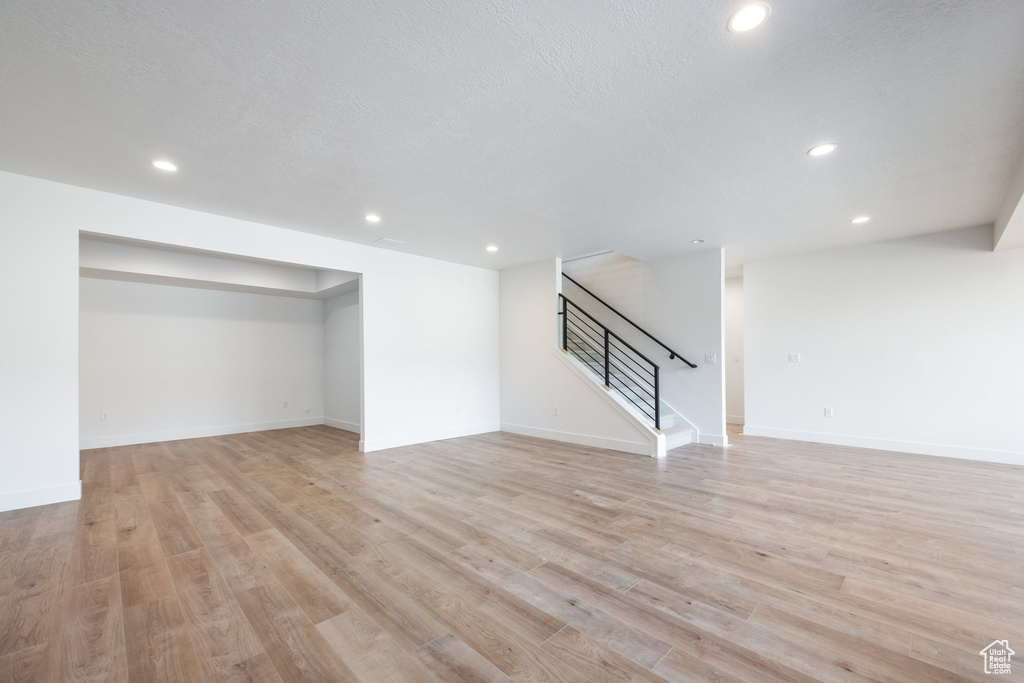Finished below grade area featuring stairway, recessed lighting, and light wood-type flooring