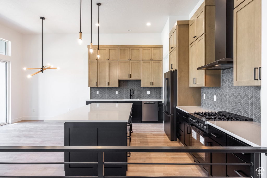 Kitchen with wall chimney range hood, freestanding refrigerator, dishwasher, range, and light countertops