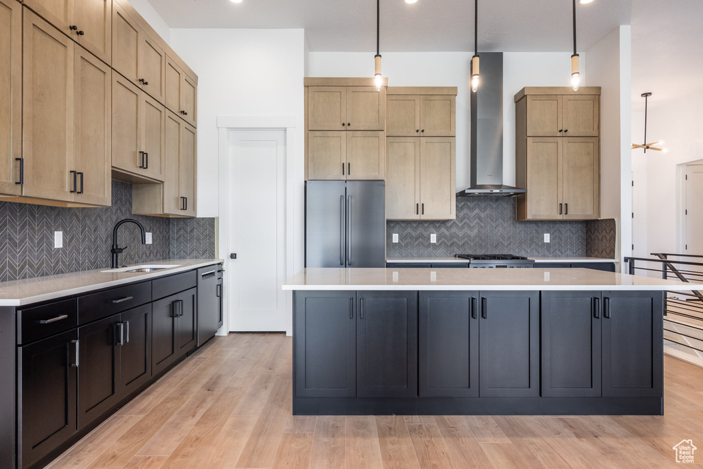 Kitchen with appliances with stainless steel finishes, light countertops, and wall chimney range hood