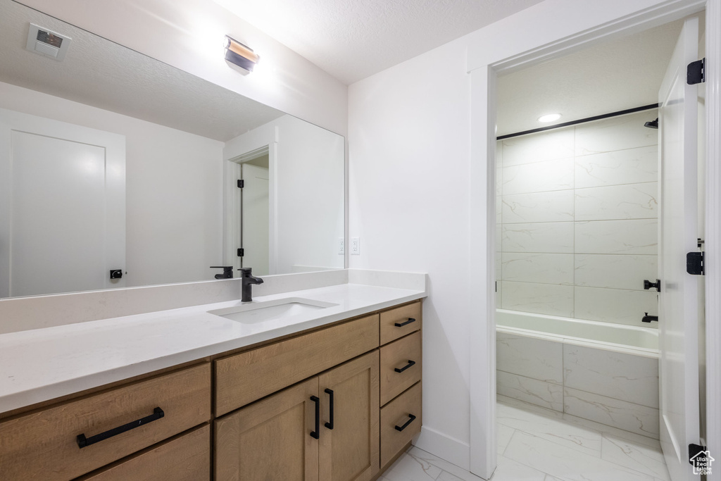 Bathroom with marble finish flooring, vanity, and a combined bath / shower with marble appearance