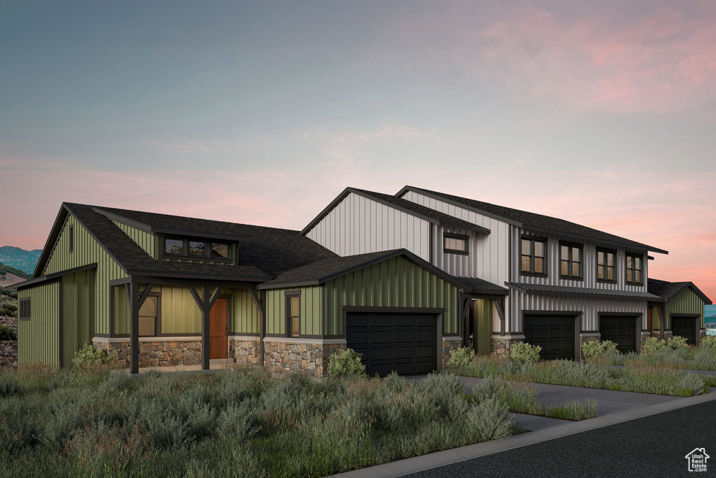 Modern inspired farmhouse featuring stone siding, a garage, concrete driveway, and board and batten siding