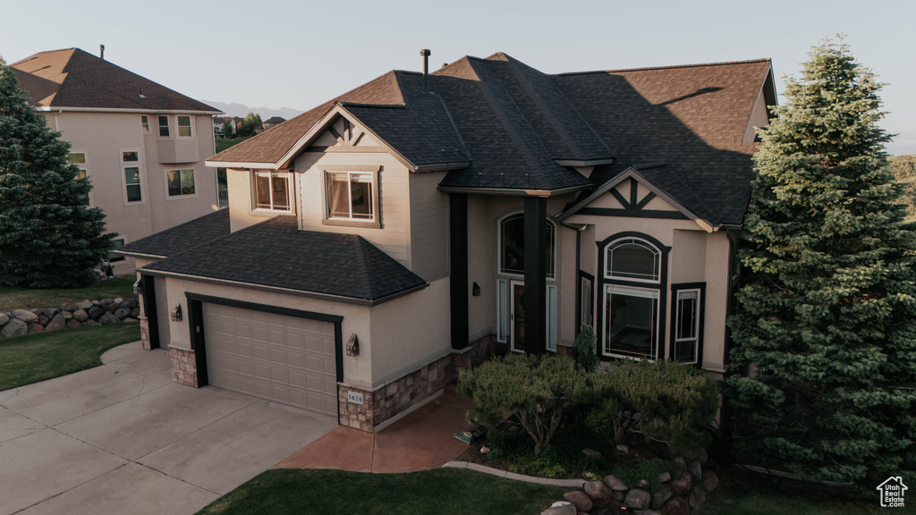View of front of property with stone siding, a shingled roof, and stucco siding