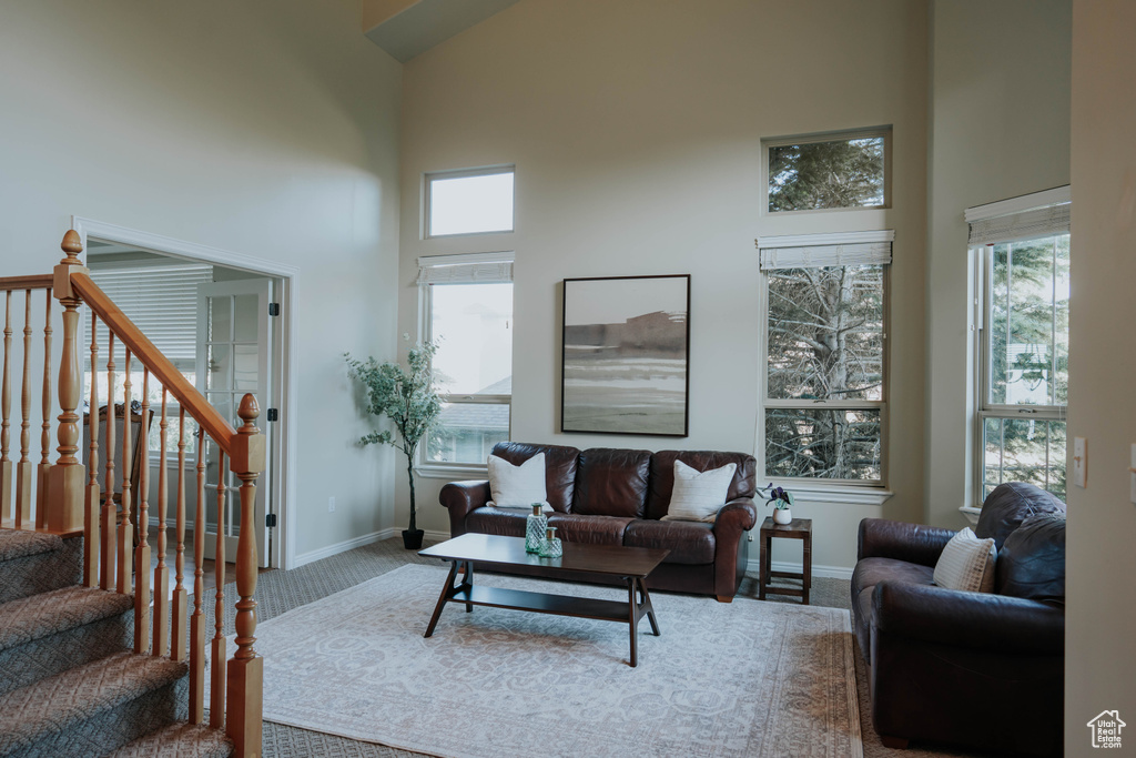 Carpeted living area featuring a high ceiling and stairway