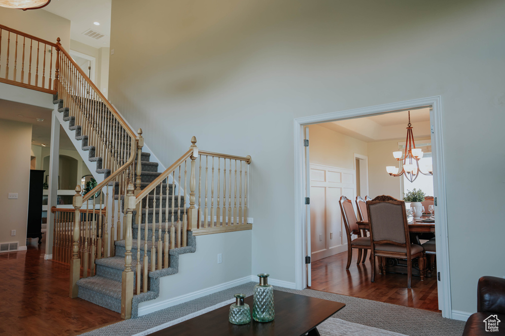 Stairs featuring wood finished floors, a chandelier, a high ceiling, and a tray ceiling