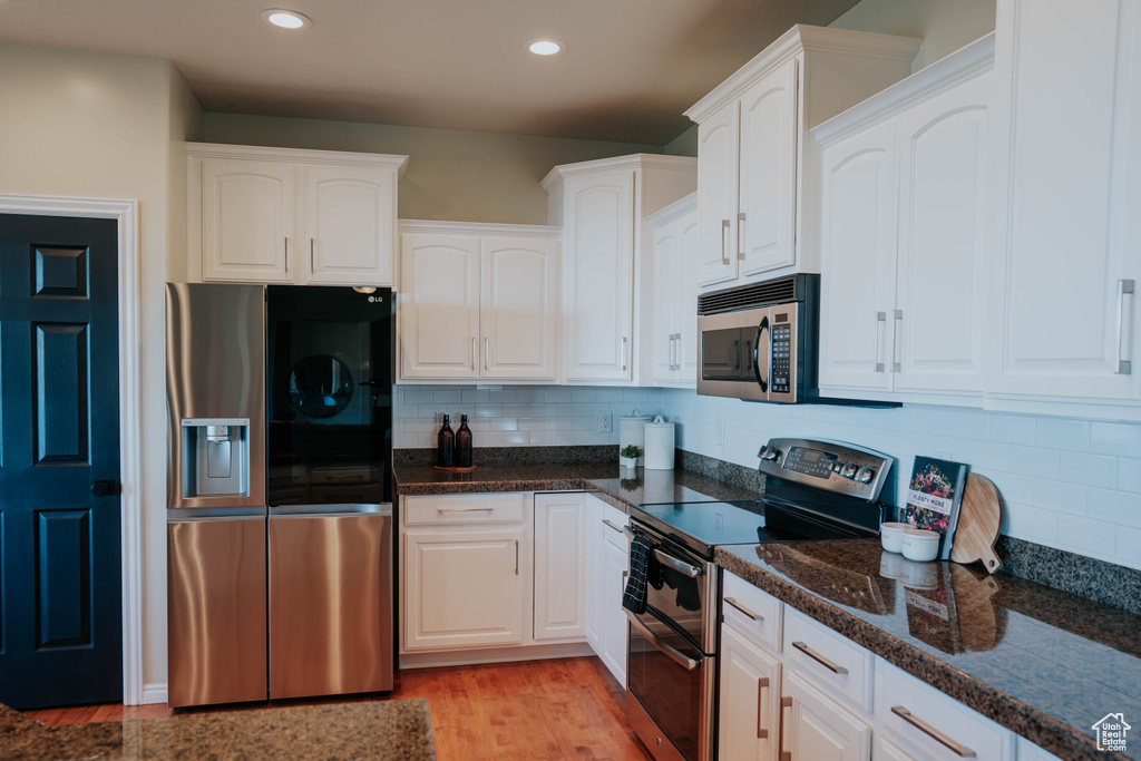 Kitchen featuring stainless steel appliances, white cabinets, decorative backsplash, and recessed lighting