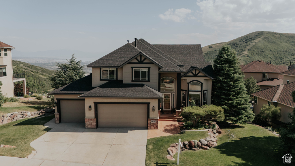 View of front of house with roof with shingles, driveway, a mountain view, and a front yard