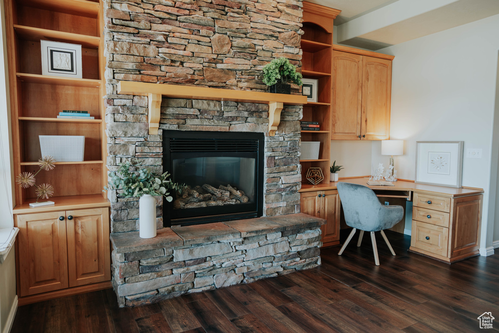 Office featuring dark wood-style floors, built in study area, and a stone fireplace