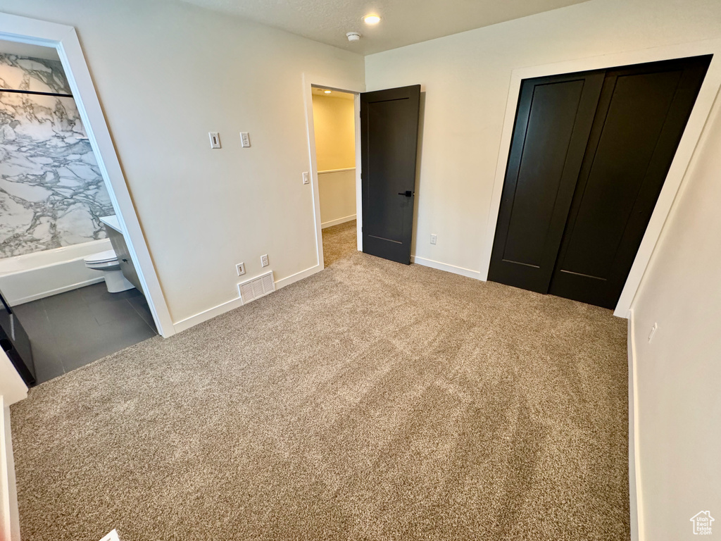 Unfurnished bedroom featuring carpet, a closet, and ensuite bathroom