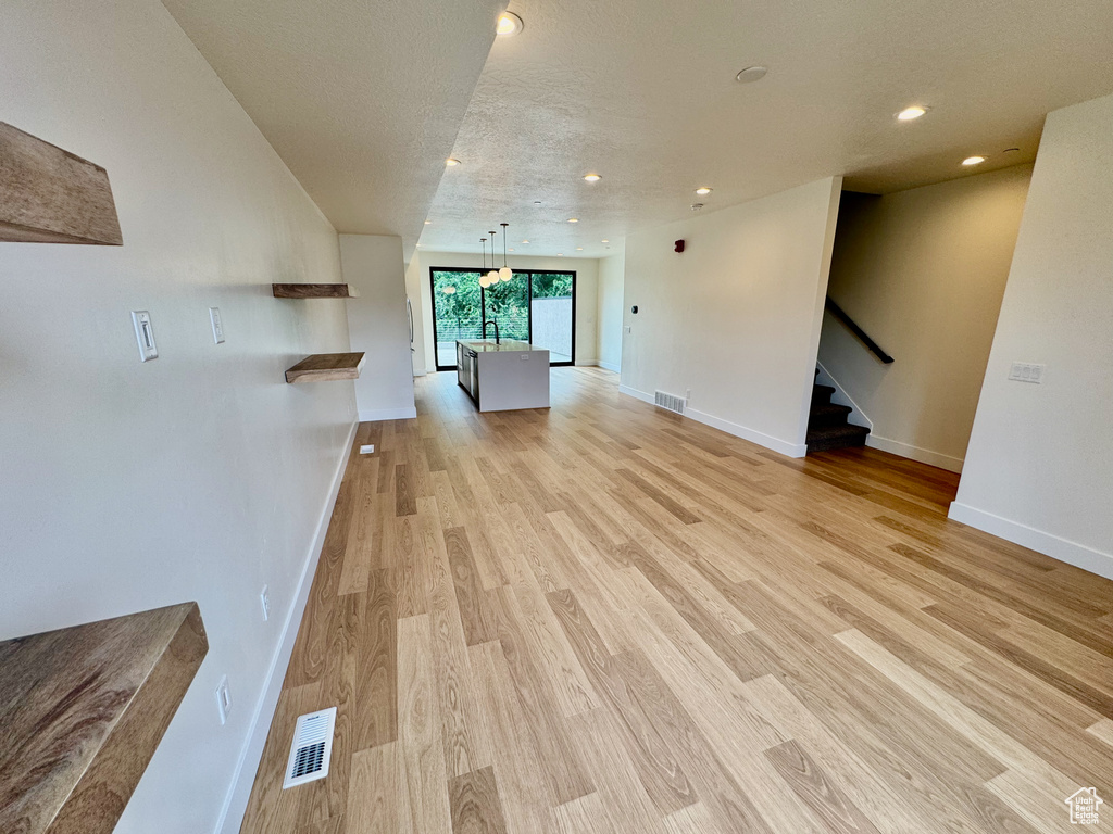 Unfurnished living room with light wood-type flooring, stairs, and recessed lighting