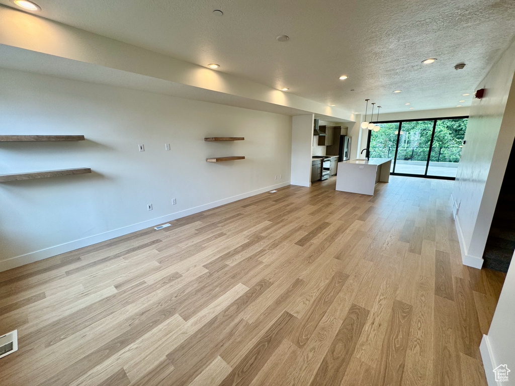 Unfurnished living room featuring light wood finished floors, recessed lighting, and a textured ceiling