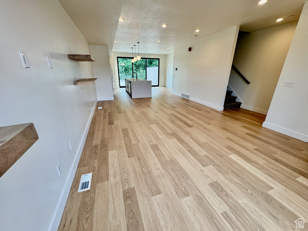 Unfurnished living room with light wood-type flooring, recessed lighting, and stairs