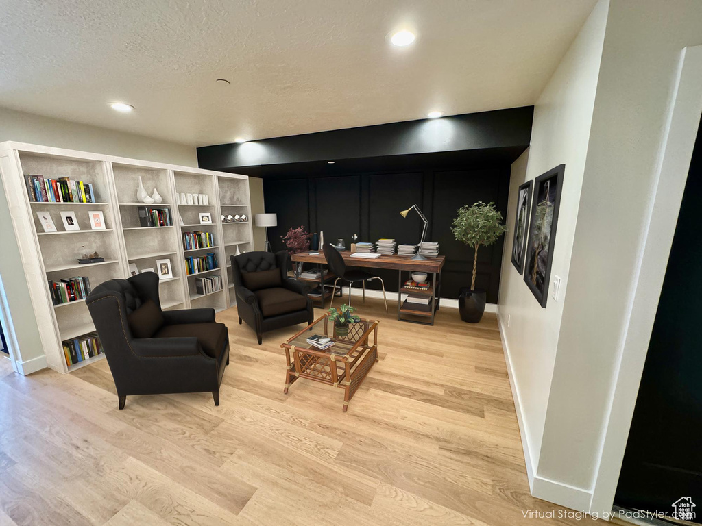 Living area with light wood-style floors, a decorative wall, a textured ceiling, and recessed lighting