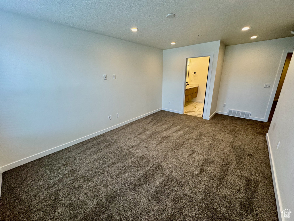 Unfurnished bedroom featuring carpet floors, recessed lighting, a textured ceiling, and ensuite bath