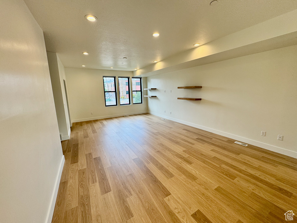 Empty room featuring light wood-type flooring and recessed lighting