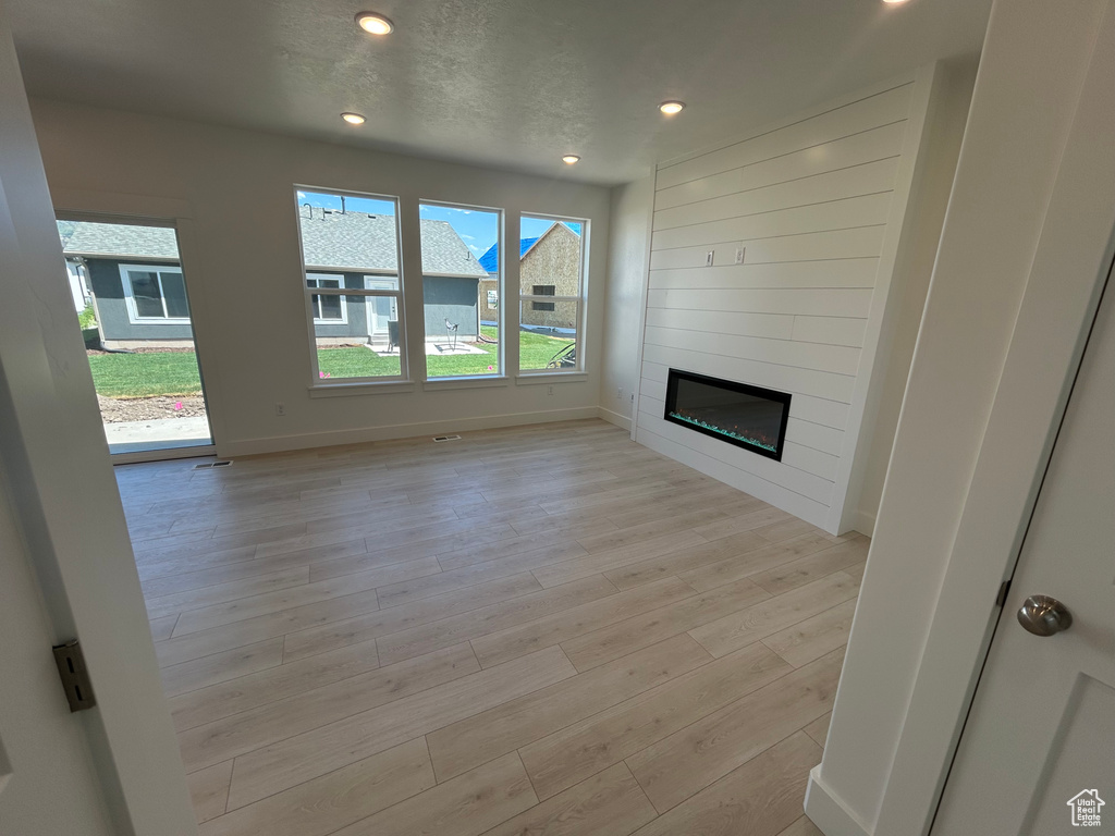 Unfurnished living room featuring light wood-style floors, a fireplace, and recessed lighting