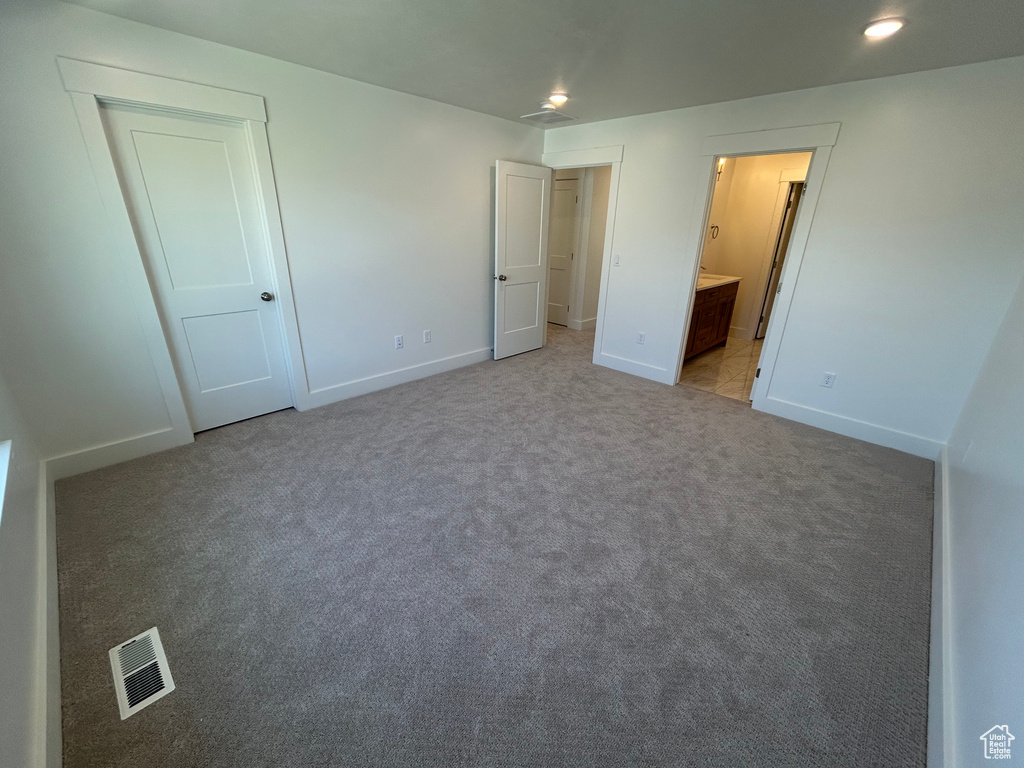 Unfurnished bedroom featuring light colored carpet, ensuite bath, and recessed lighting