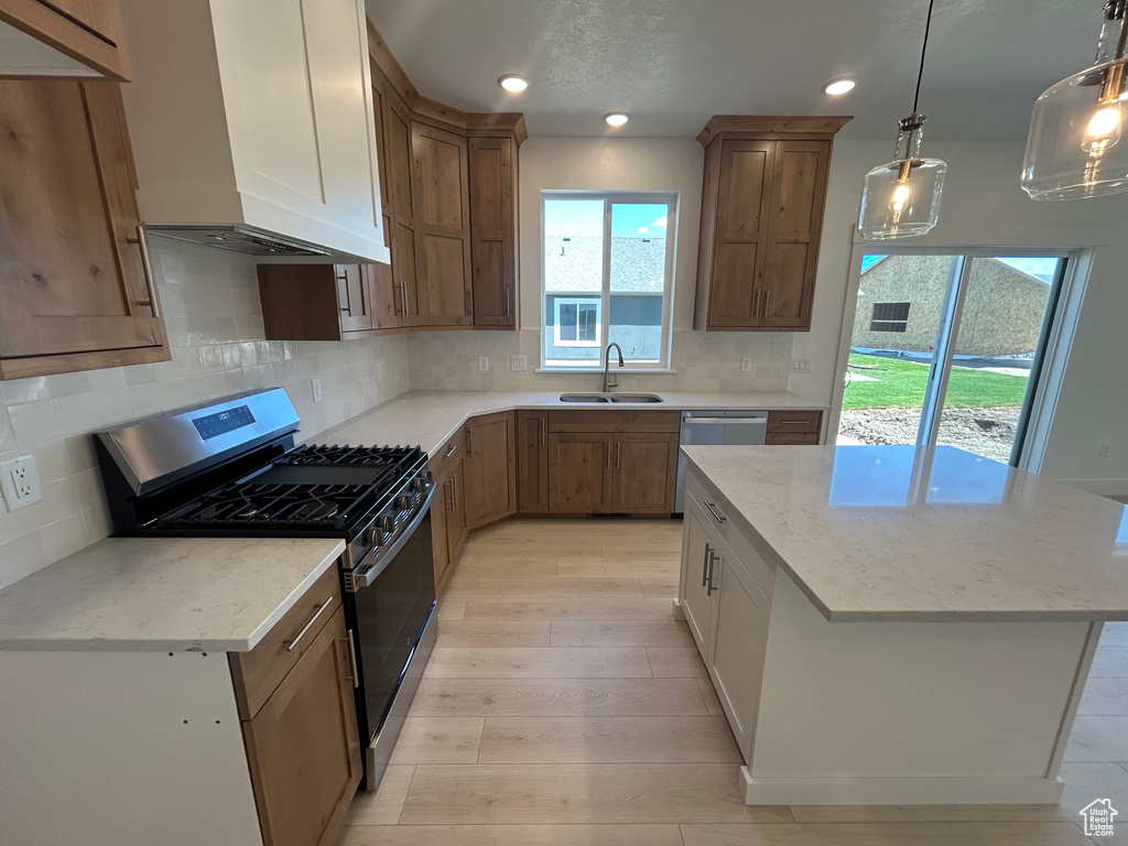 Kitchen featuring stainless steel appliances, custom exhaust hood, light wood-type flooring, a kitchen island, and light stone countertops
