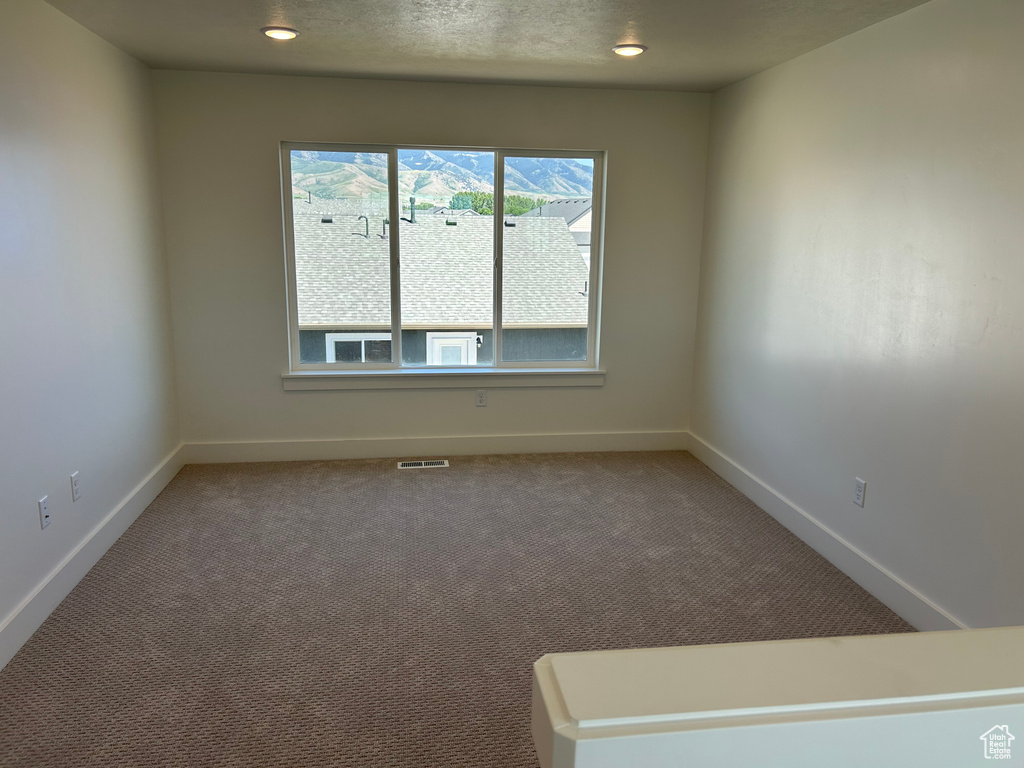 Carpeted spare room featuring baseboards