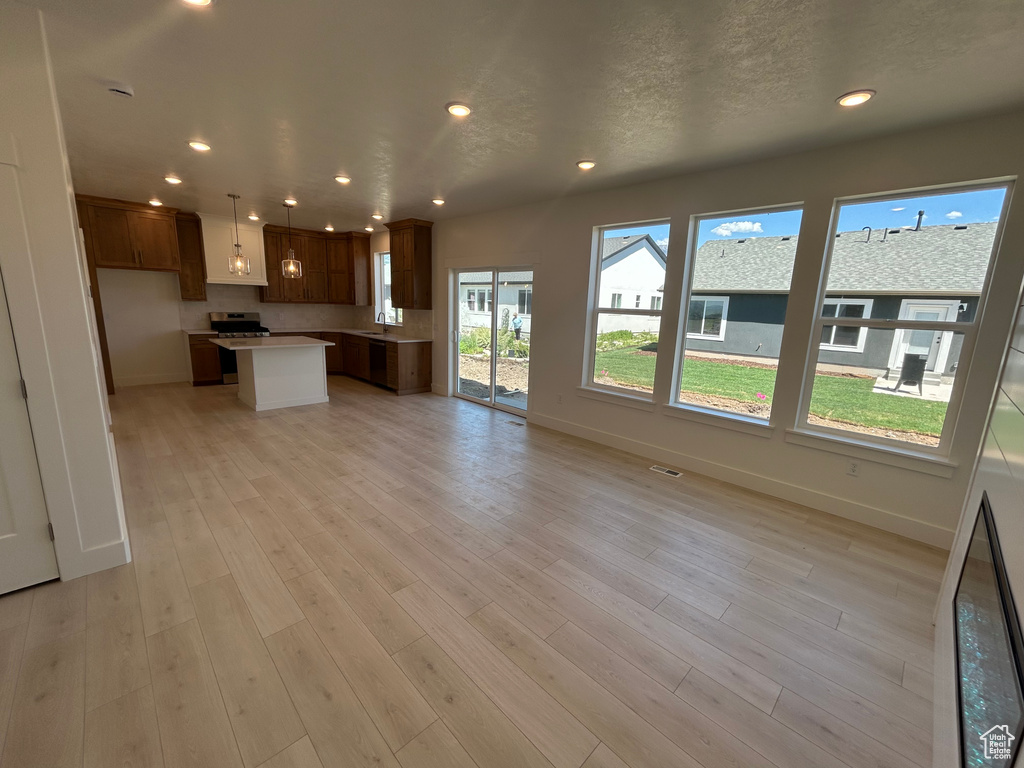 Kitchen with open floor plan, recessed lighting, light wood-type flooring, a center island, and light countertops