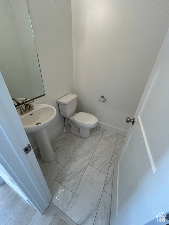 Bathroom featuring marble look tile flooring and toilet