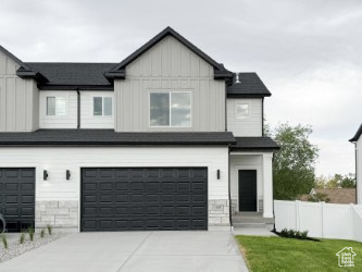 Modern farmhouse with board and batten siding, a garage, and driveway